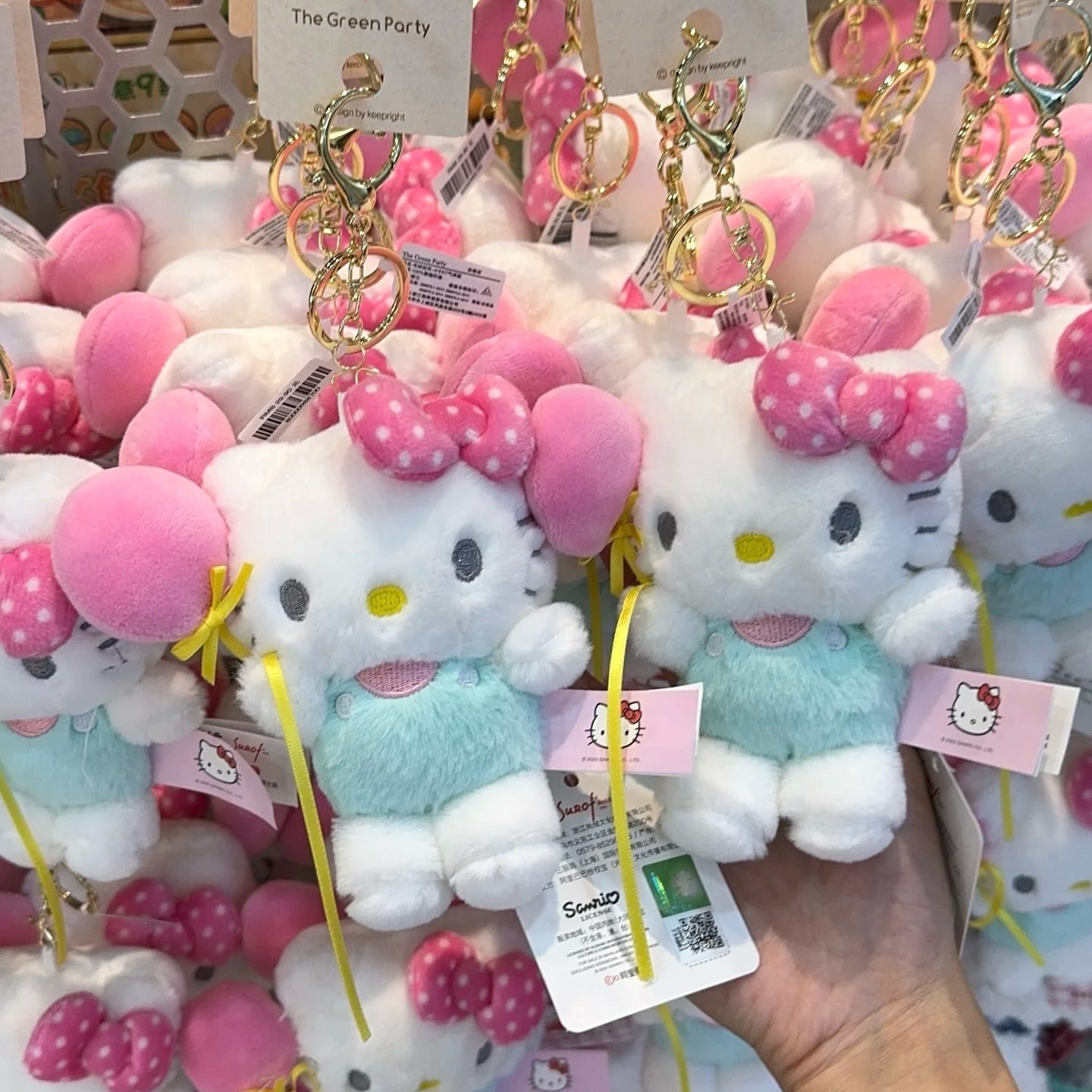 Hello Kitty plush toys with keychains on display in a store.